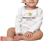 a baby sitting on the floor wearing a birthday shirt