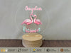 a clear acrylic sign with two pink flamingos