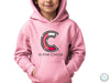 a child wearing a pink hoodie with the letter c on it