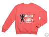 a pink sweatshirt with the words shine your light on it