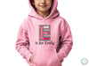 a young boy wearing a pink hoodie with the letter e on it