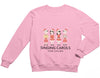 a pink sweatshirt with three people wearing santa hats and singing carols for choir